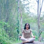 a woman sitting on top of a rock in a forest