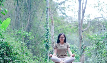 a woman sitting on top of a rock in a forest